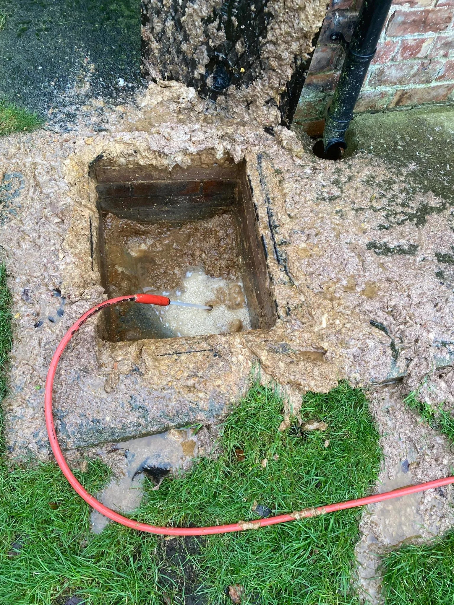 Expert drain clearance using high-pressure jetting on a blocked manhole.