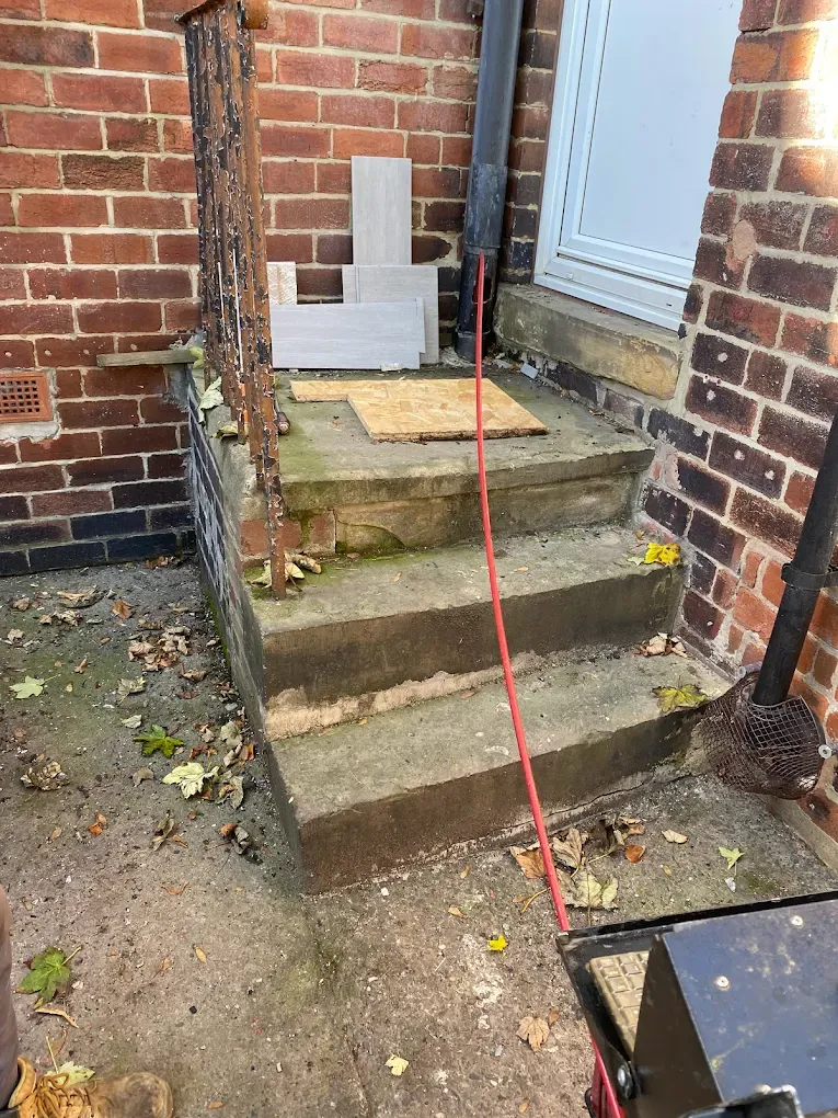 Drainage cleaning equipment next to an exterior downpipe and gully at a home.