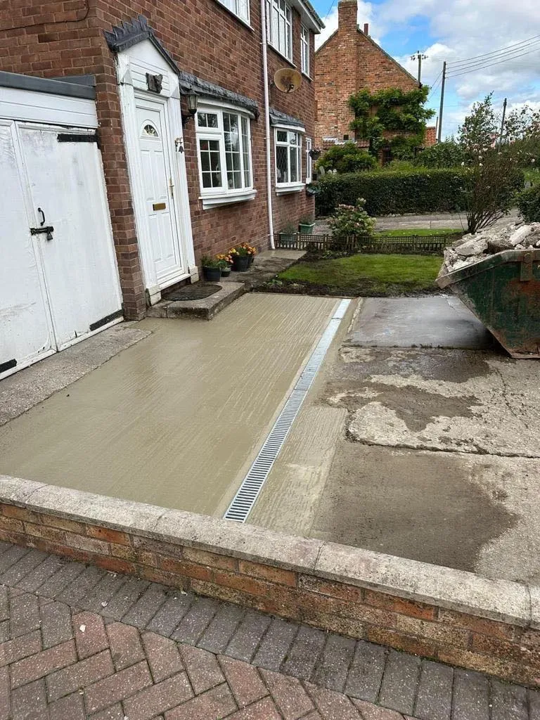 Professional installation of a surface water channel drain in a newly laid concrete driveway.