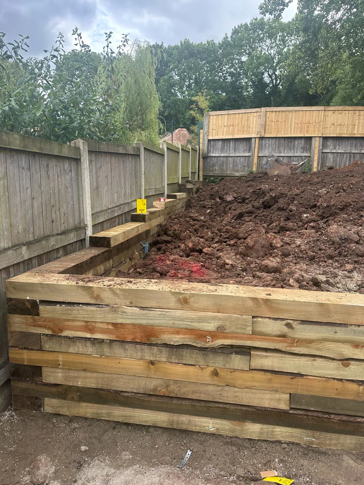 Excavation and groundworks for drainage installation in a garden.