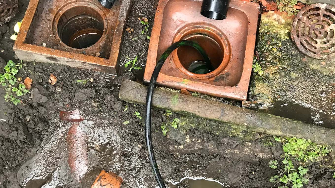 Outdoor drainage gullies with a hose inserted for service.